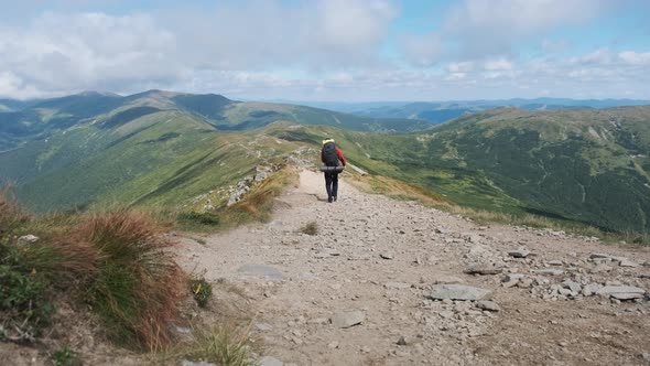 Tourist with a Backpack Goes Down Along the Stone Mountain Trail on the Hill alt