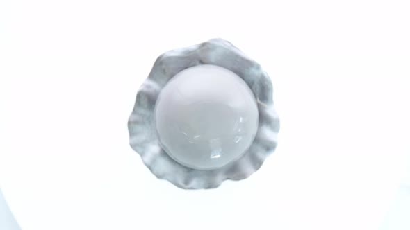 Dessert in the Form of Pearl with Gray Glaze Spinning on White Background alt