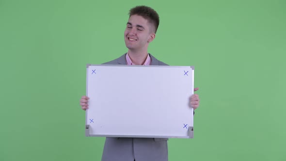 Happy Young Businessman Thinking While Holding White Board alt