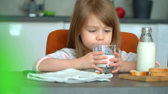 Little Girl Drinks Milk in Kitchen