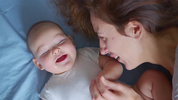 Close Up Shot of Young Mother is Playing with Her Newborn Baby in a Nursery in a Morning alt
