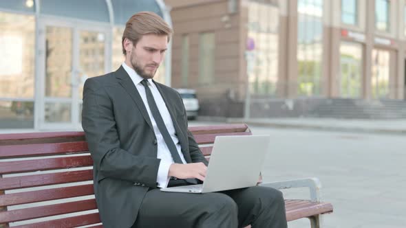 Rejecting Businessman in Denial While Using Laptop Sitting Outdoor on Bench alt