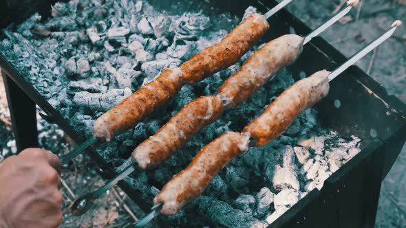 Sausages on Skewers are Cooked on the Portable Grill Outdoor Close Up BBQ alt
