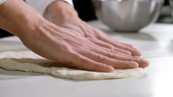Professional baker prepares dough for traditional Italian pizza