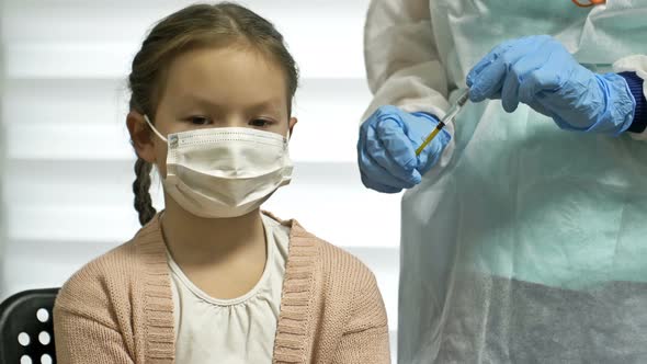 Nurse in a Protective Uniform and a Medical Mask Gives an Injection of the Covid19 Vaccine to a alt