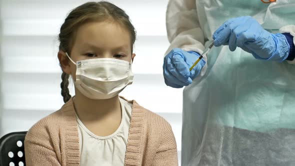 Nurse in a Protective Uniform and a Medical Mask Gives an Injection of the Covid19 Vaccine to a
