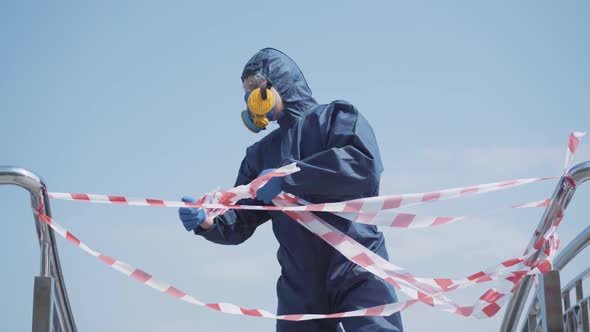Man in Chemical Suit Tearing Off Caution Tape and Leaving. Portrait of Caucasian Young Guy in alt