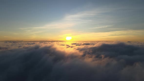 Aerial View of Vibrant Yellow Sunrise Over White Dense Clouds with Blue Sky Overhead alt
