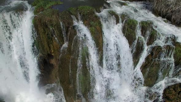 Flying view of waterfall flowing over edge into river alt