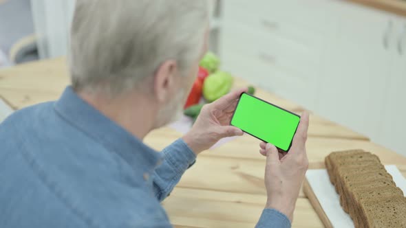 Rear View of Old Man Using Smartphone with Chroma Key Screen alt