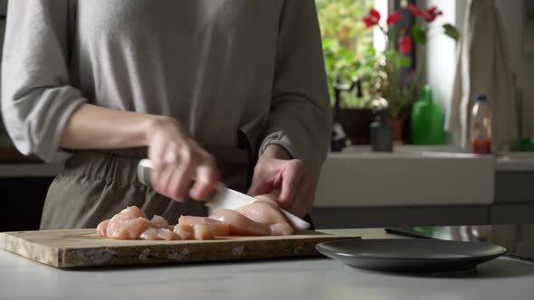 woman cuts chicken breast before cooking alt