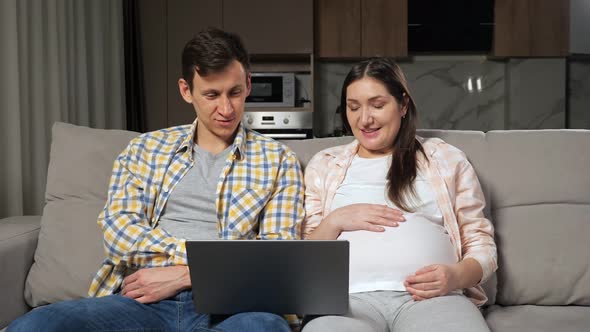 Husband and Pregnant Wife Do Shopping Online Sitting on Sofa alt