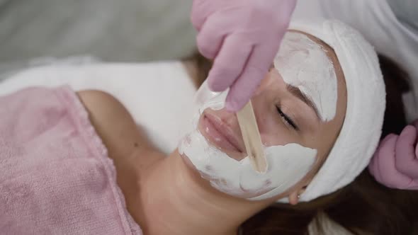 Applying Clay Mask with Spatula on Female Face in a Beauty Salon alt