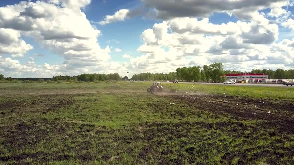 Back Motion From Tractor Birds Fly Pecking Grain on Field alt
