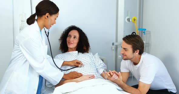 Doctor examining pregnant woman with stethoscope in ward alt