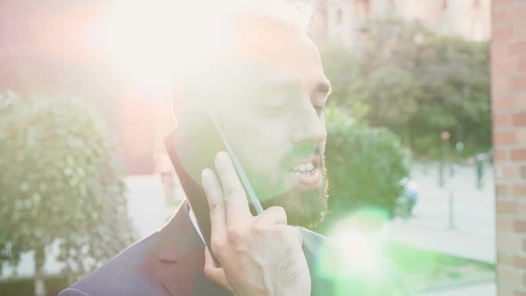 Businessman on the Phone in the City with the Sun Behind His Head alt