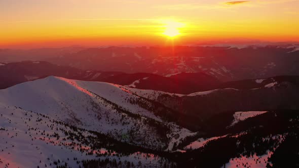 Flying above Winter mountain. During Sunrise or Sunset. Red, orange colored Sky.  alt