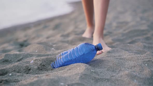 Barefoot Volunteer Removing Blue Bottle From Shore