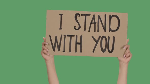 Female Hands Hold a Poster From a Cardboard Box with the Words I STAND WITH YOU. Protest Against alt