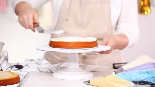 Step by step. Pastry chef stacking cake layers with buttercream frosting between to create unicorn c alt
