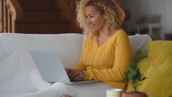 Blond woman working on laptop sitting on couch