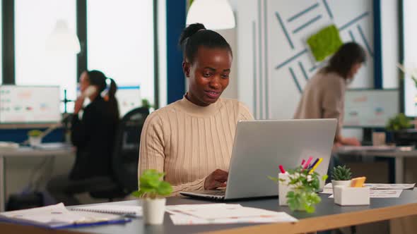 Happy Black Manager Reading Tasks on Laptop and Typing Sitting at Desk alt