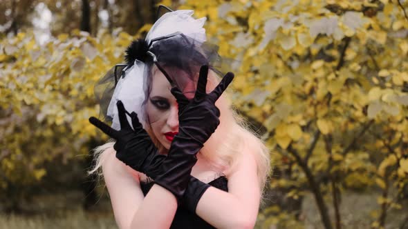 A beautiful girl in the image of a witch with black eyes and red lips. With black gloves. Dancing. H alt