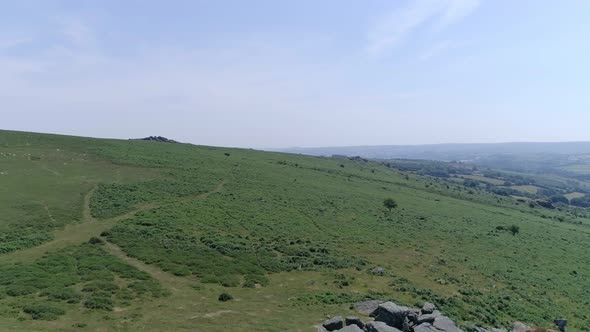 Wide shot aerial tracking forward over the wide expanse of Dartmoor, tors, grassy moorland and rocky alt