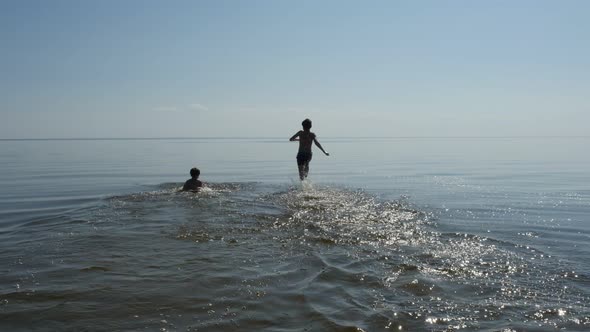 Two Boys Running Into Sea Water in Sunny Day