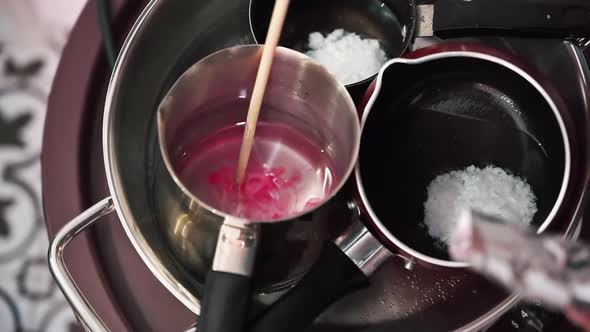 Hand made candles production, female hand mixing dye and melting wax in pots. Slow motion alt