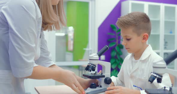 Teacher Helps Students to Adjust the Laboratory Microscope to Work alt