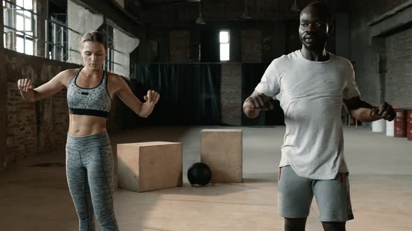 Fitness couple warming up, doing arms stretching exercise at gym alt