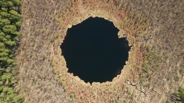 AERIAL: Top View of Round Deep Blue Lake in Forest