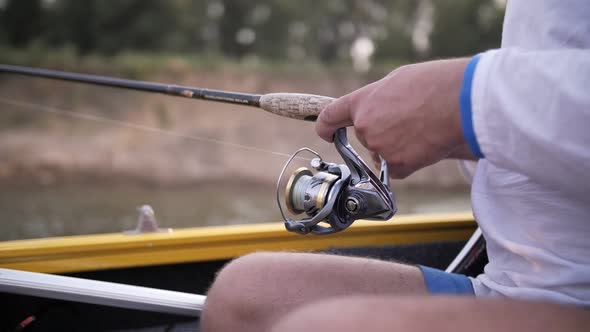 a man catches fish on a fishing rod from a boat