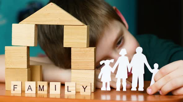 A caucasian boy of 6-7 years old holds a paper-cut silhouette of a family in his hands. Inscription alt