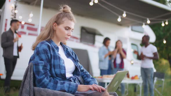 Caucasian Female Freelance Working at a Laptop While Sitting Near Camping Car Typing Text and Remote alt