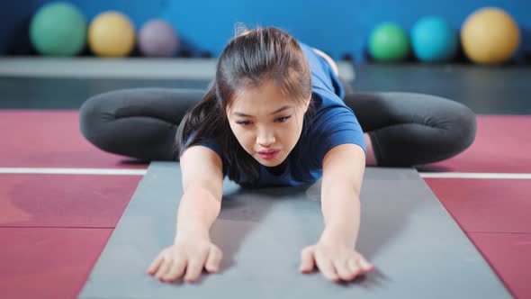 Diligent Young Asian Fitness Woman Making Stretching Reach Hands Forward During Sitting on Rug alt