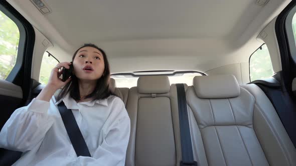 Happy asian woman having phone call on backseat in car alt