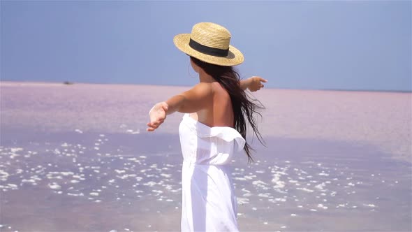 Woman in Hat Walk on a Pink Salt Lake on a Sunny Summer Day.