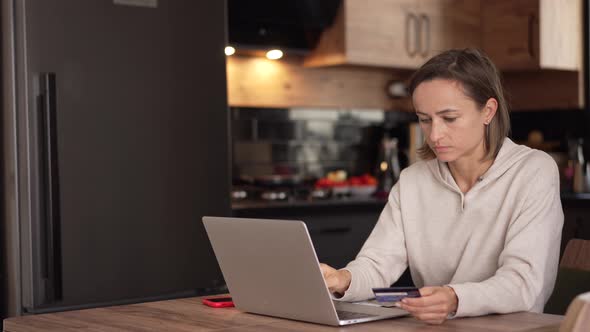 Caucasian Woman Makes an Online Payment Using a Bank Card and Laptop alt