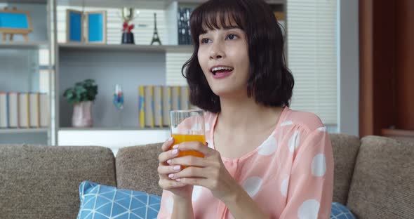 Asian young pretty woman drinking orange juice on sofa 