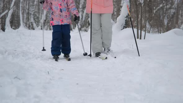 Little Girl with Mother Skiing in Winter Forest alt