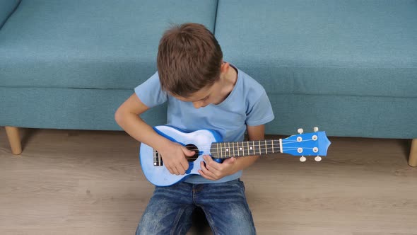A Child Learns to Play a Small Guitar alt
