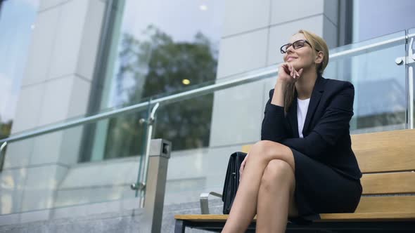 Female Entrepreneur Sitting on Bench, Smiling, Rejoicing at Successful Day alt