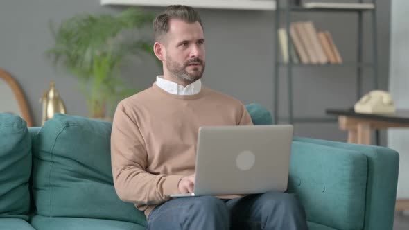 Man with Laptop Thinking on Sofa alt