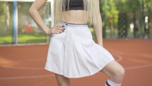 Camera Moves Up Along Gorgeous Slim Body of Young Confident Cheerleader Posing on Outdoor Basketball alt