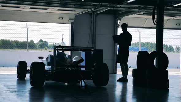 A Specialist with a Laptop is Visually Inspecting a Racing Car alt