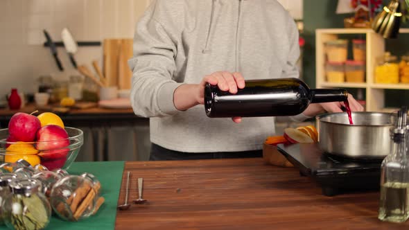 Woman Cooking Mulled Wine Gluhwein with Apples and Oranges Recipe alt