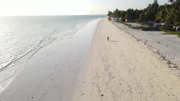 A Man Rides a Bike Along the Beach in Zanzibar Tanzania alt
