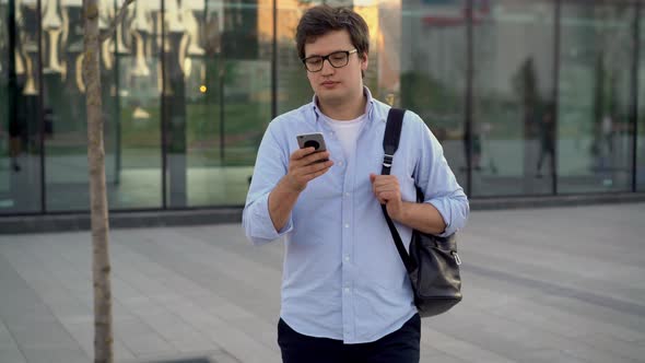 Gimbal Shot of Man with a Smartphone on Background of Glass Windows